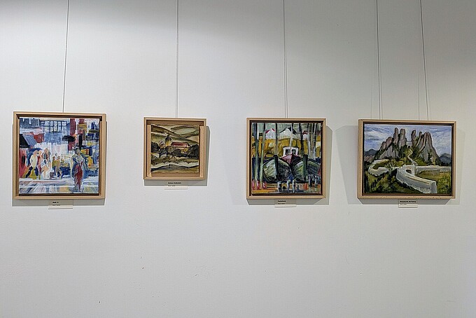 An einer weißen Wand hängen vier Gemälde.