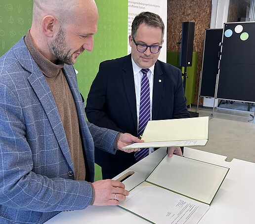 Rektor Prof. Dr.-Ing. Alexander Kratzsch und Landrat Dr. Stephan Meyer betrachten den Kooperationsvertrag der HSZG und des Landkreises Görlitz.