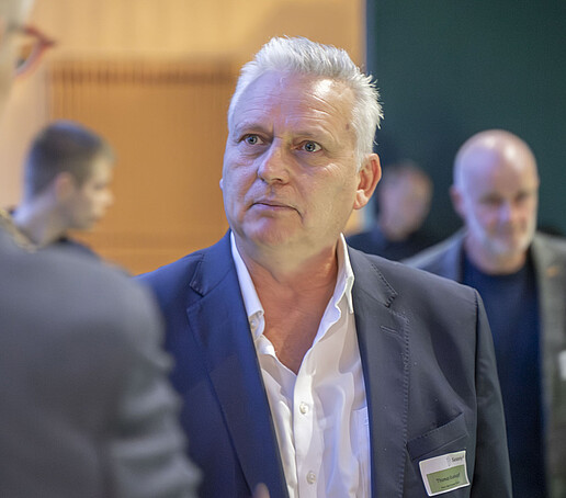 Ein älterer Herr unterhält sich mit einem anderen Gast der Veranstaltung.