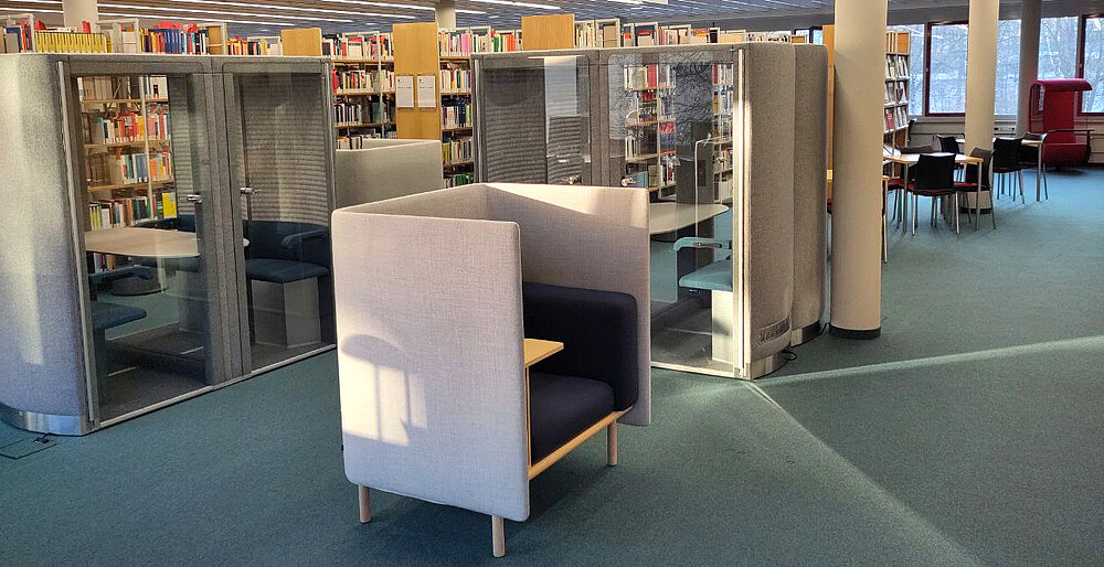 Blick in den Leseraum, Sessel im Vordergrund, Flüsterboxen und Regale im Hintergrund
