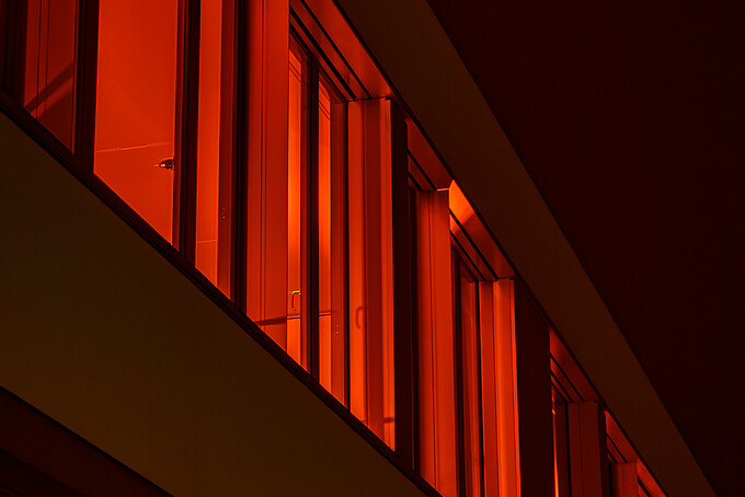 Nach Sonnenuntergang erstrahlt aus den Fenstern des Gebäudes Z vier orangenes Licht.