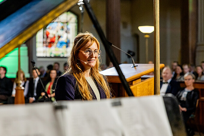 Victoria Hohlfeld steht singend neben dem Flügel und blickt in Richtung des Publikums.