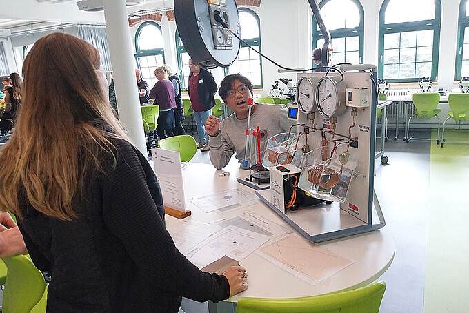 Zwei Menschen probieren eine Experimentierstation aus.