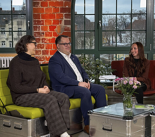 Der Rektor sitzt mit weiteren Gästen auf dem grünen Sofa im TV-Studio und beantwortet Interviewfragen.