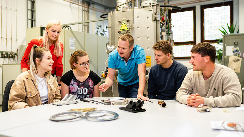 Studierende sitzen im Maschinenwesen-Labor und hören einem Lehrbeauftragten zu.